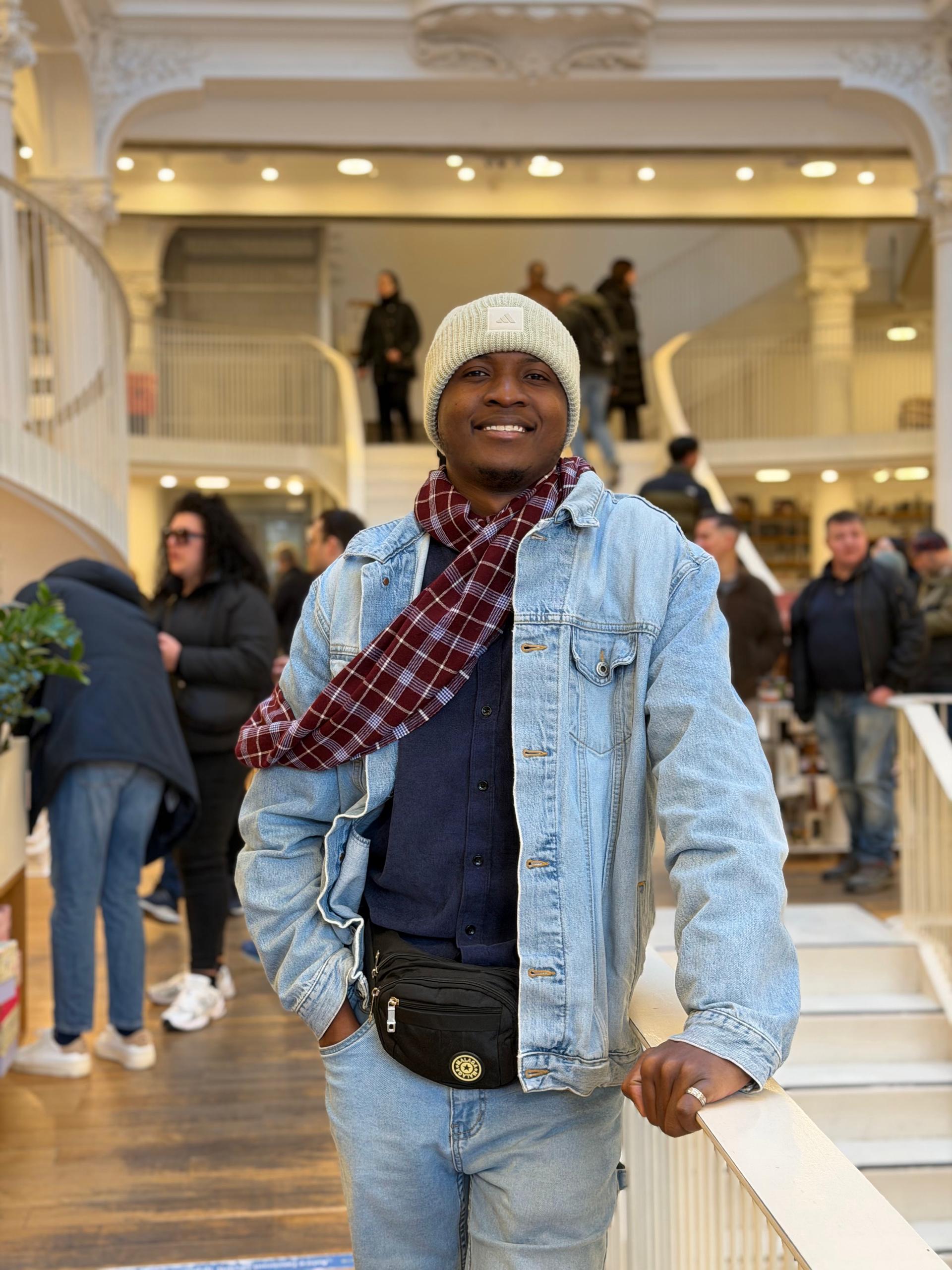 Anthony bending toward the camera and smiling beside a colourful cultural display